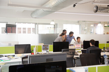 Business people brainstorming at computer in open plan office
