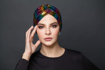 Young attractive woman in turban on black background portrait