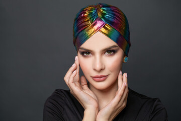 Fashion model woman in ethnic turban on head on black background