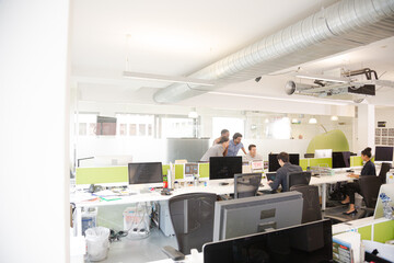 Business people brainstorming at computer in open plan office