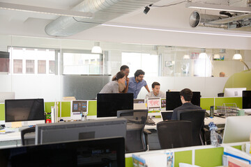 Business people brainstorming at computer in open plan office