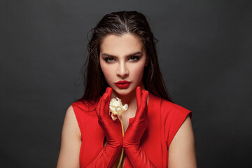 Lady in red evening dress with white flowers. Stylish woman in red gloves, fashion model on black portrait