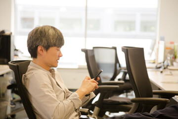 Portrait confident businessman using smartphone in office