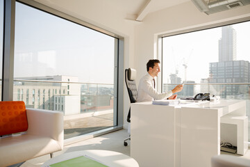 Naklejka na ściany i meble Businessman working at desk in modern office