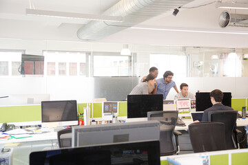 Business people brainstorming at computer in open plan office