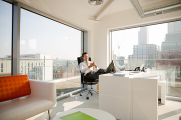 Businessman relaxing at desk in modern office