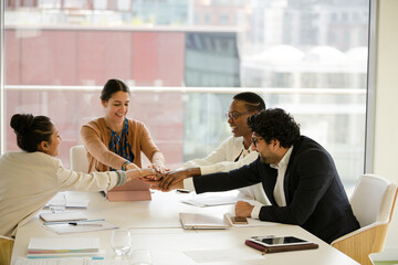 Business people touching hands, celebrating success in conference room