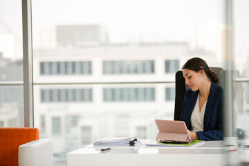 Businesswoman using smartphone and tablet computer at desk