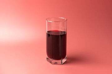 a glass of pomegranate juice on a red background