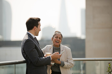 Businessman and businesswoman enjoying coffee on balcony, talking