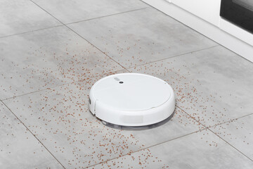 Washing White robot vacuum cleaner device cleaning floor from crumbs groats at home on utonite...