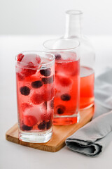 Two tall glasses of cranberry juice in front of bottle