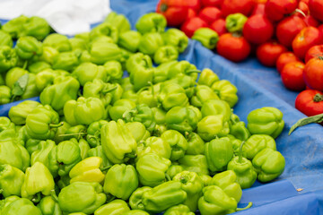 Green bell peppers and tomatoes on vegetable market.