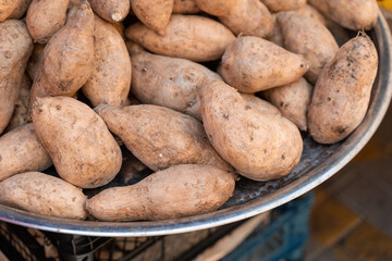 Sweet potatoes named batata on counter market on background of lemons.