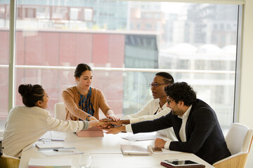 Business people touching hands, celebrating success in conference room