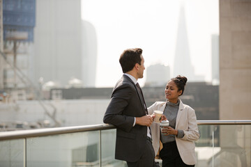 Businessman and businesswoman enjoying coffee on balcony, talking