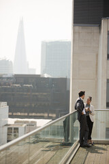 Businessman and businesswoman enjoying coffee on balcony, talking