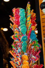 Caramel colored lollipops for children on sticks at entrance to market