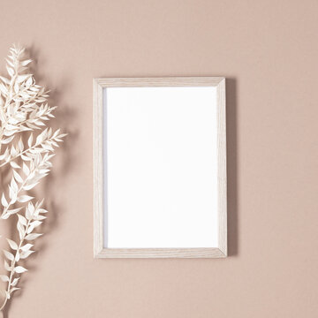 Wooden photo frame mockup with dry plant on beige background. Autumn composition. Flat lay, top view, copy space