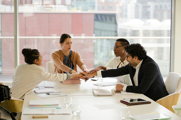 Business people touching hands, celebrating success in conference room