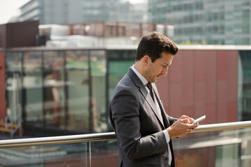 Businessman using smartphone on balcony