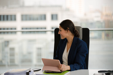 Businesswoman using smartphone and tablet computer at desk