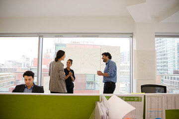 Business people discussing diagram sketches hanging on office window