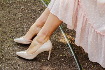Legs of a woman wearing high heel shoes and a soft pink, nude dress
