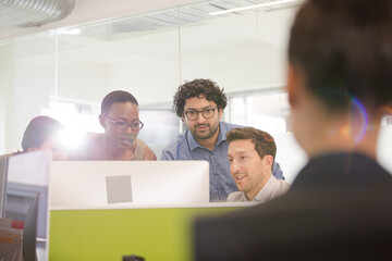 Business people brainstorming at computer in open plan office