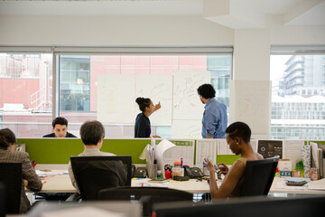 Business people discussing diagram sketches hanging on office window