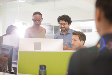 Business people brainstorming at computer in open plan office