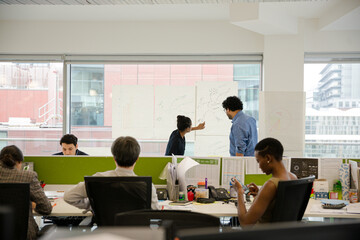 Business people discussing diagram sketches hanging on office window