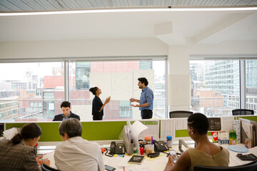 Business people discussing diagram sketches hanging on office window