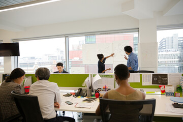 Business people discussing diagram sketches hanging on office window