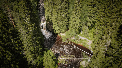 the river flows fast, descending smoothly on stone rapids, stone coast, reddish river, green forest...