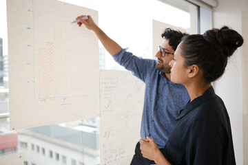 Business people discussing diagram sketches hanging on office window