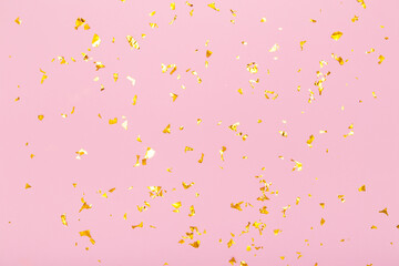 Golden glitter confetti sparkles on pastel pink background. Flat lay, top view. Holiday, festive, party backdrop