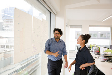 Business people discussing diagram sketches hanging on office window