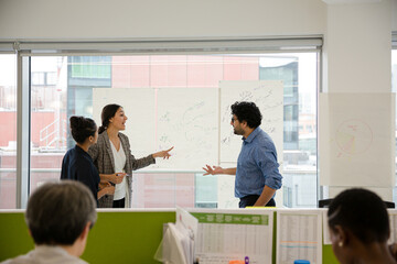 Business people discussing diagram sketches hanging on office window