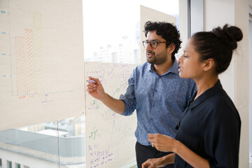 Business people discussing diagram sketches hanging on office window
