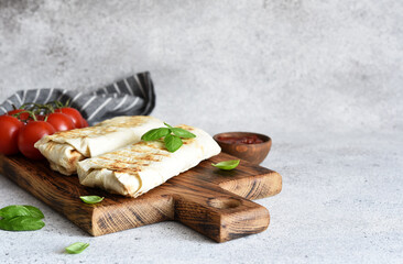 Shawarma with meat and vegetables on a wooden board on the kitchen table. Shawarma slice.