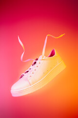 Footwear poster - white leather sneakers shoe on the pink and orange background