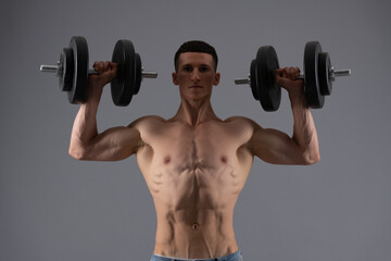 Fototapeta na wymiar Strongman with muscular torso lift dumbbells in strong arms biceps triceps grey background, strength