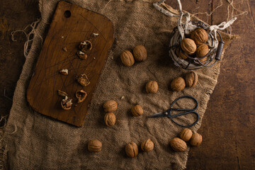 Walnuts on burlap with scissors and cutting board flatlay