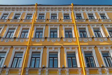 Fototapeta na wymiar Typical building facade yellow and white color with windows in Saint-Petersburg on sunny day, Russia
