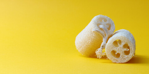 Loofah sponges on yellow background with copy space. Natural luffa sponge eco lifestyle concept.