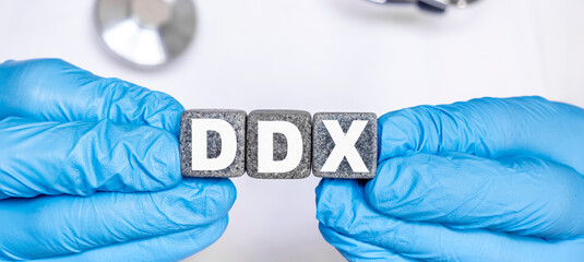 DDX Differential diagnosis - word from stone blocks with letters holding by a doctor's hands in medical protective gloves - obrazy, fototapety, plakaty