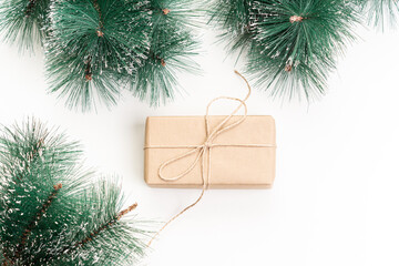 Gift in eco-friendly paper package and spruce branches on white background. Gift for Christmas