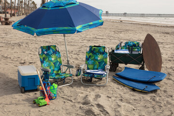 Fun at the beach with an ice chest, umbrella, chairs, toys, boogie boards, wagon, beach towels, and skimboard