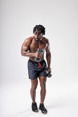 Shirtless Muscular Afro Man With Naked Torso Holding Dumbbells In Hands, Exercising In Studio On White Background. Portrait Of Good-looking Healthy Guy Pumping Muscles With Sports Equipment